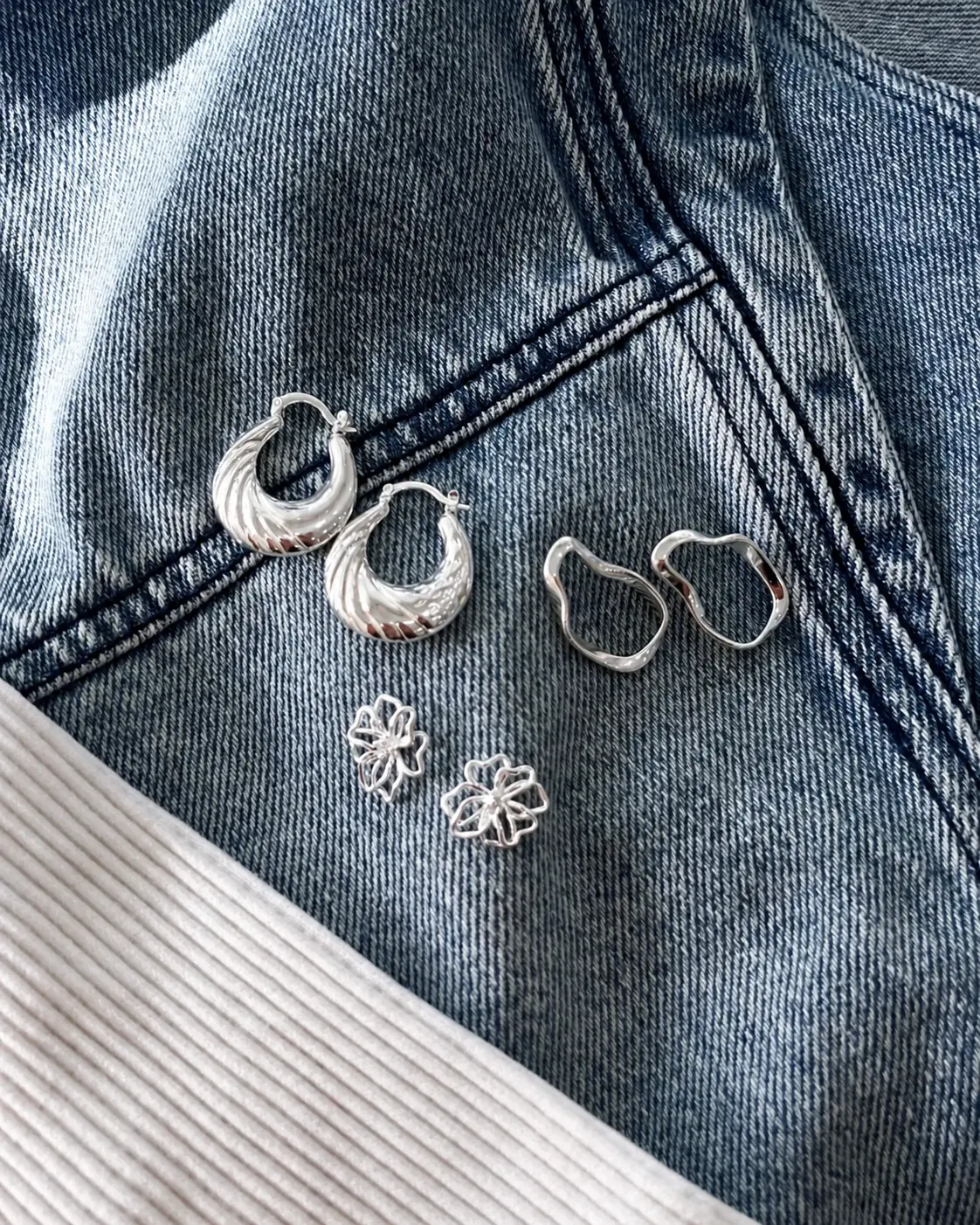 Argolas e brincos de prata BARG sobre jaqueta jeans